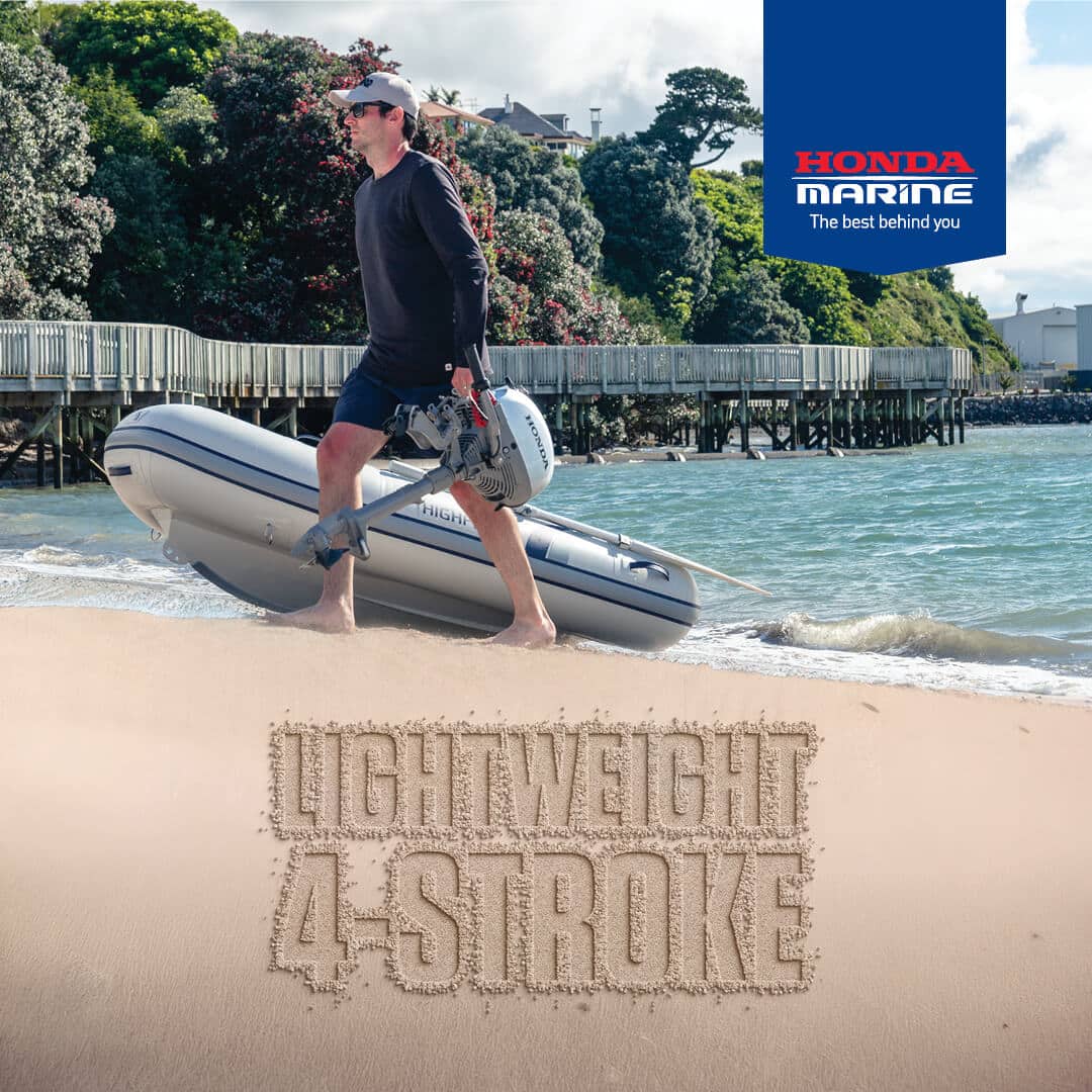 Man walks with a small inflatable boat on a sunny beach; sand reads 'LIGHTWEIGHT 4-STROKE' with Honda Marine logo in the corner.