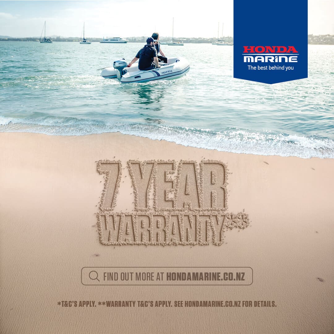 Two people ride a white inflatable boat on calm water near a sandy shore; in the foreground the words '7 YEAR WARRANTY' are etched in the sand with a Honda Marine banner in the top-right corner.
